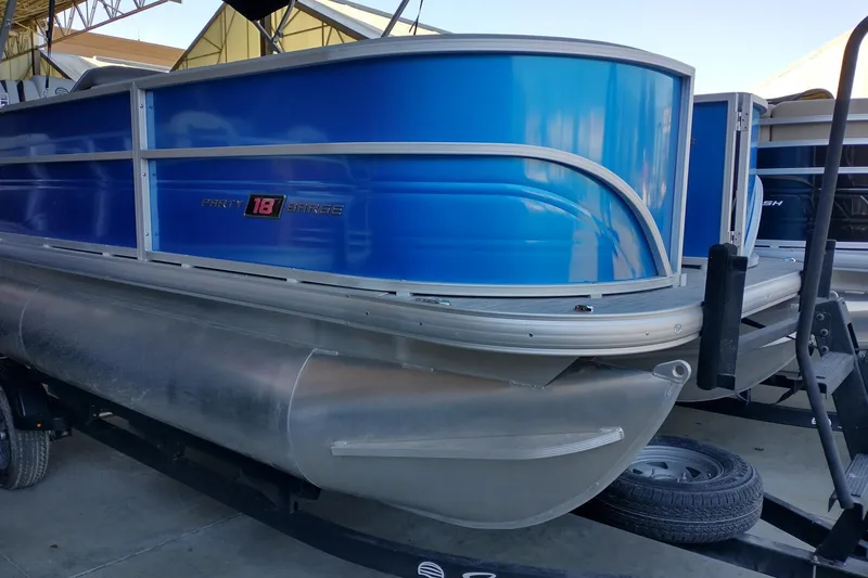Slide: The Image of 2026 Sun Tracker Party Barge 18 DLX pontoon boat with blue exterior on trailer. - 2