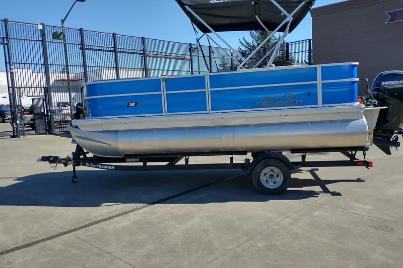 Slide: The Image of 2026 Sun Tracker Party Barge 18 DLX pontoon boat on trailer, parked outdoors. - 6
