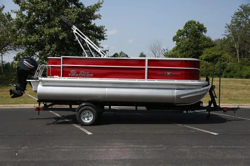 The Image of 2026 Sun Tracker Party Barge 18 DLX pontoon boat on trailer in parking lot. - 0