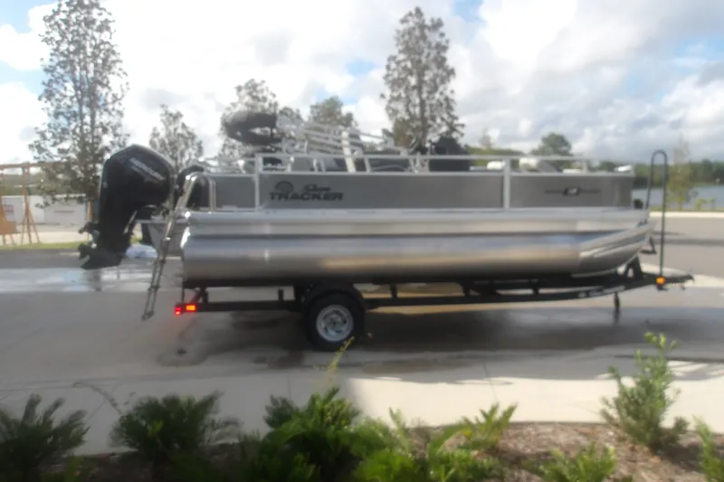 The Image of 2026 Sun Tracker Bass Buggy 18 DLX pontoon boat on trailer, parked outdoors. - 1