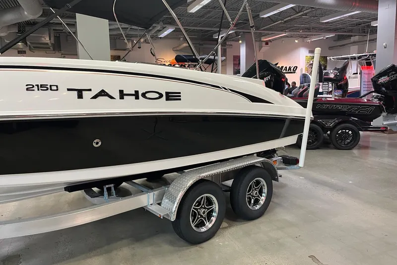 Slide: The Image of 2026 Tahoe 2150 boat on display in showroom, featuring sleek black and white design. - 2