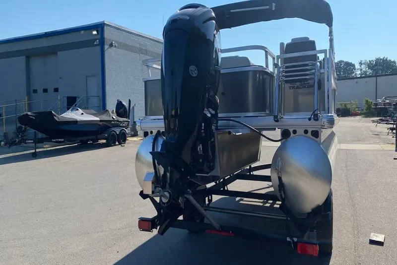 Slide: The Image of 2026 Sun Tracker Bass Buggy 18 DLX pontoon boat on trailer, parked outdoors. - 86