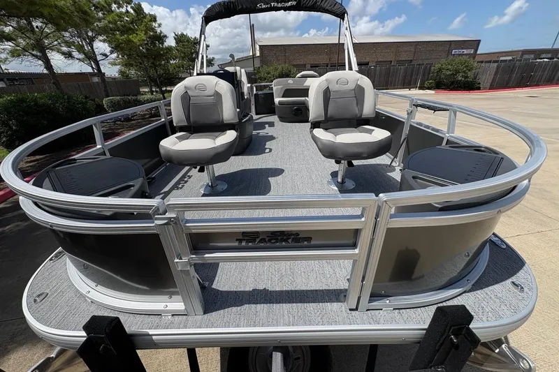 Slide: The Image of 2026 Sun Tracker Bass Buggy 18 DLX pontoon boat with seating, parked outdoors. - 93