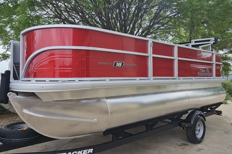 The Image of 2026 Sun Tracker Party Barge 18 DLX pontoon boat with red exterior on trailer. - 0