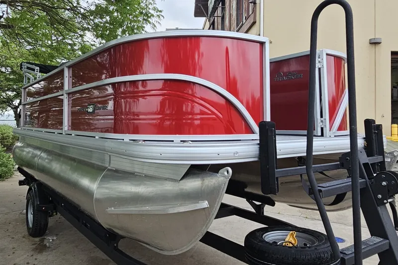 Slide: The Image of 2026 Sun Tracker Party Barge 18 DLX pontoon boat with red exterior on trailer. - 2
