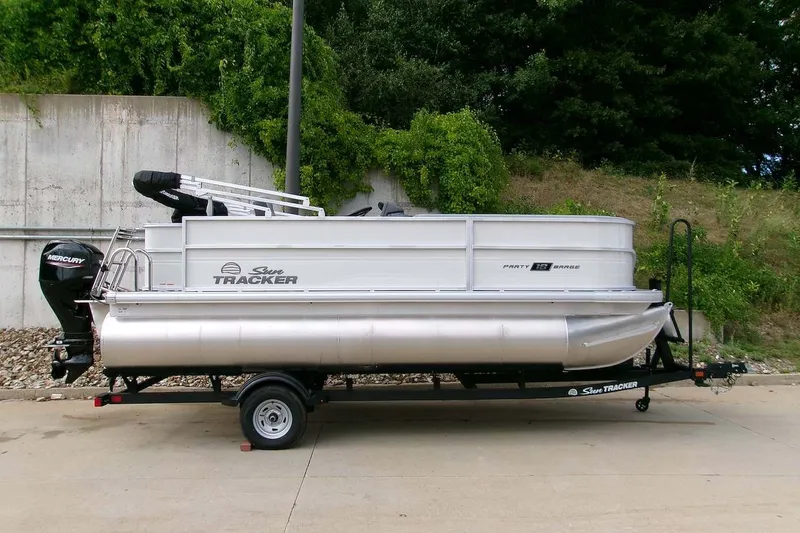 The Image of 2026 Sun Tracker Party Barge 18 DLX pontoon boat on trailer, parked outdoors. - 0