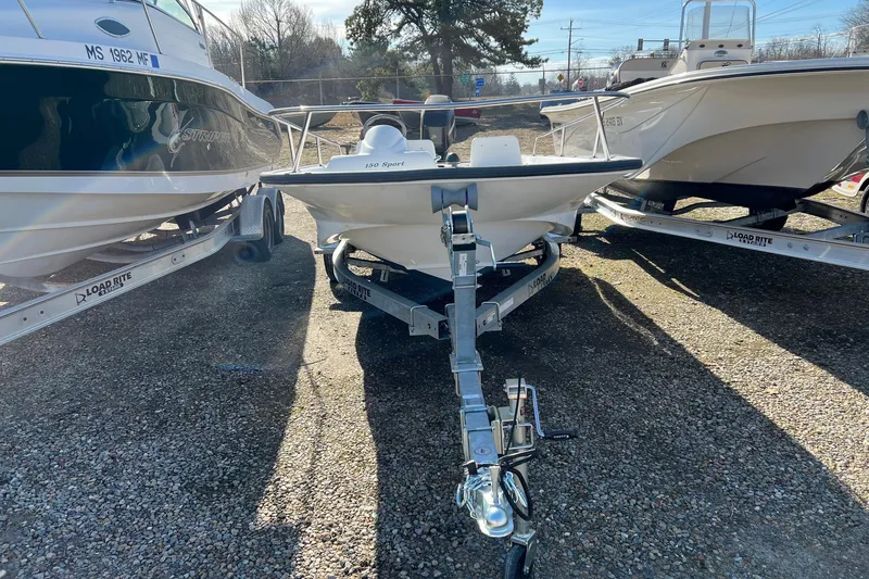 Slide: The Image of 2006 Boston Whaler 150 Sport boat on trailer, parked between two other boats. - 3