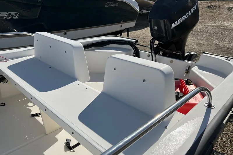 Slide: The Image of 2006 Boston Whaler 150 Sport boat interior with Mercury engine, featuring white seating. - 5