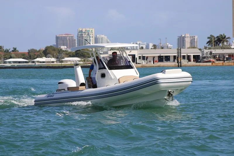 Slide: The Image of 2026 Brig Eagle 8 boat cruising on clear blue water near urban shoreline. - 9