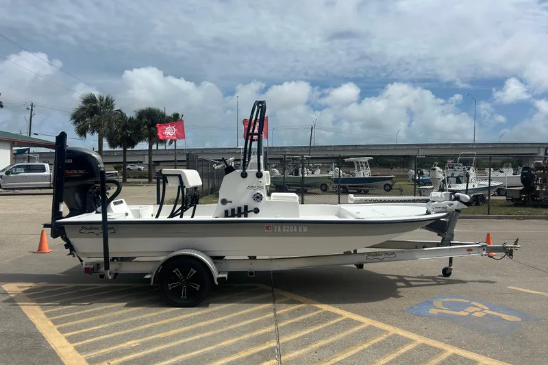 Slide: The Image of 2023 Shallow Sport 18 Sport boat on trailer, parked outdoors under cloudy sky. - 2