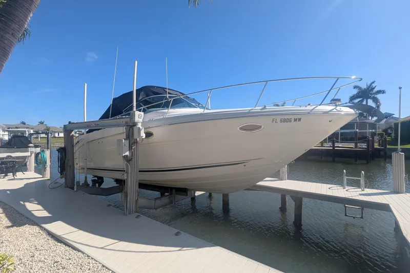 The Image of 2005 Sea Ray 290 Amberjack boat docked on a lift under clear blue skies. - 0