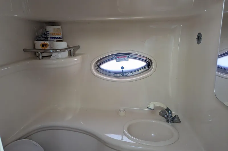Slide: The Image of 2005 Sea Ray 290 Amberjack bathroom with sink, oval window, and toiletries. - 12