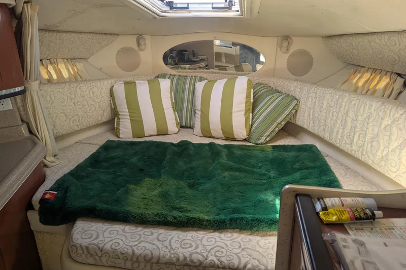Slide: The Image of Cozy cabin interior of 2005 Sea Ray 290 Amberjack with striped pillows and green blanket. - 13