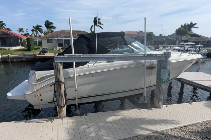 Slide: The Image of 2005 Sea Ray 290 Amberjack boat docked on a lift by waterfront homes. - 4
