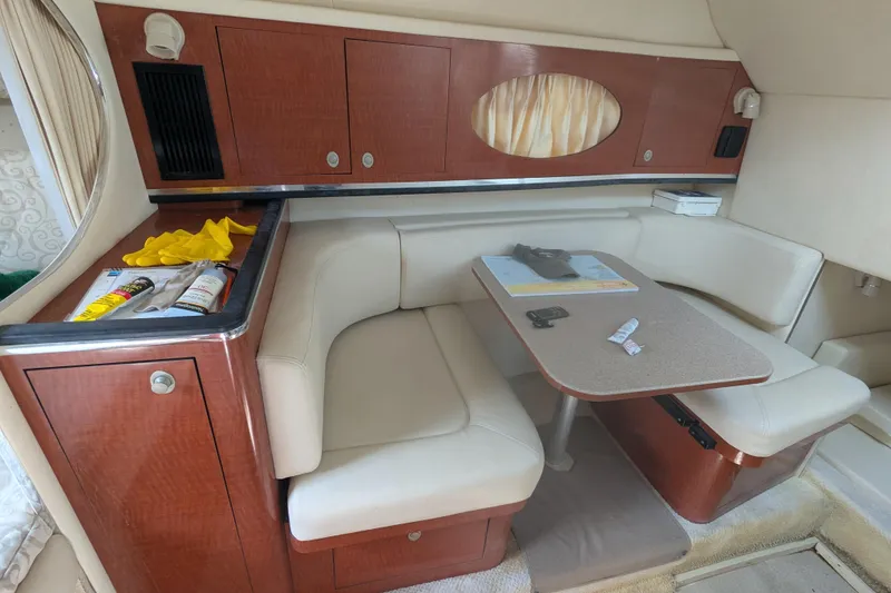 Slide: The Image of 2005 Sea Ray 290 Amberjack cabin interior with seating and table, featuring wood cabinetry. - 45