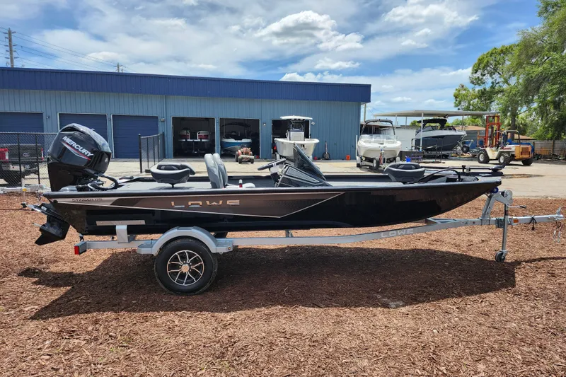 Slide: The Image of 2026 Lowe Stinger 175C boat on trailer, parked outside a blue warehouse. - 3