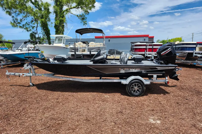Slide: The Image of 2026 Lowe Stinger 175C fishing boat on trailer, parked outdoors under a clear sky. - 7