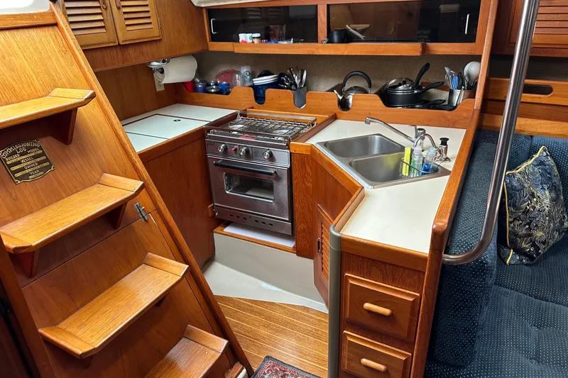 Slide: The Image of 1987 O'Day 40 yacht interior kitchen with wooden cabinetry, stove, and sink. - 8