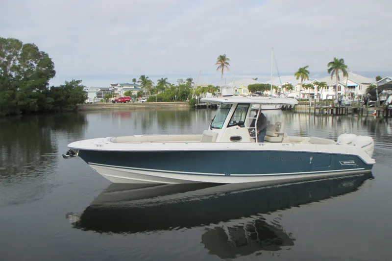 The Image of 2018 Boston Whaler 330 Outrage boat on calm water near a marina. - 0