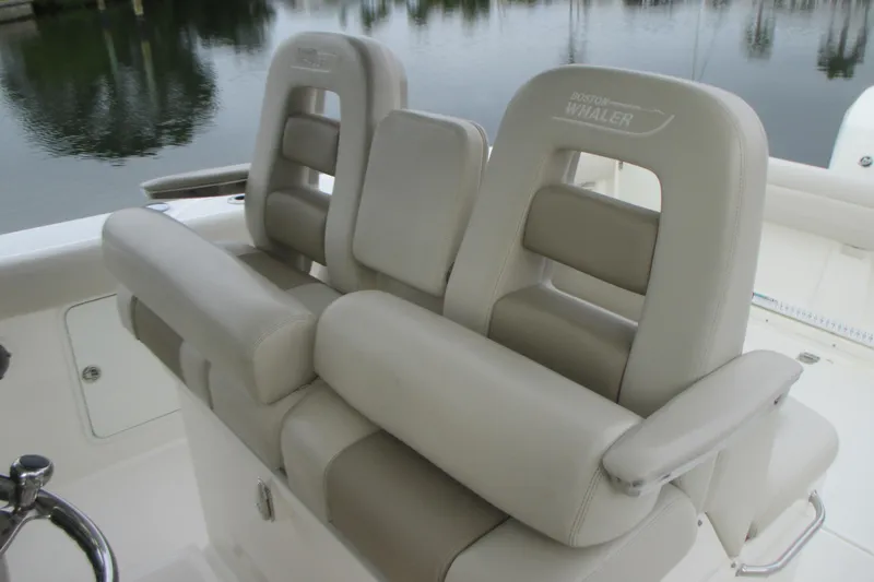 Slide: The Image of 2018 Boston Whaler 330 Outrage boat seats, beige leather, docked by calm water. - 14