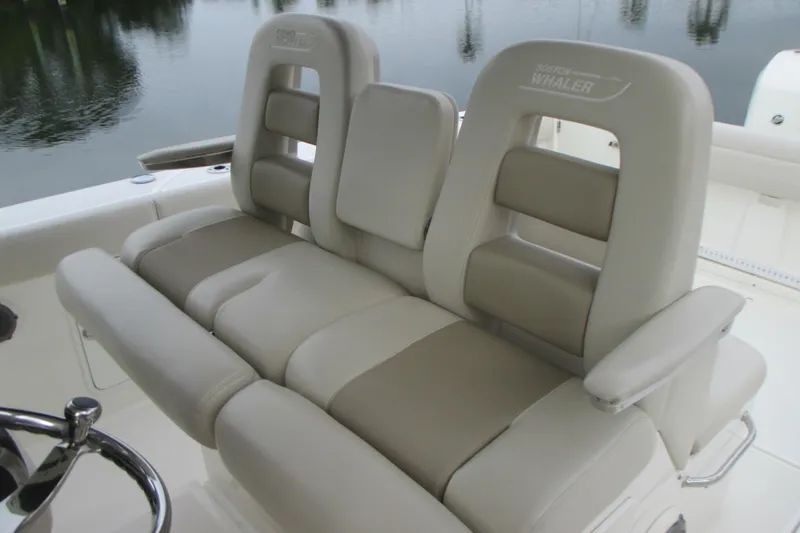Slide: The Image of 2018 Boston Whaler 330 Outrage boat seats, featuring beige upholstery and armrests. - 15