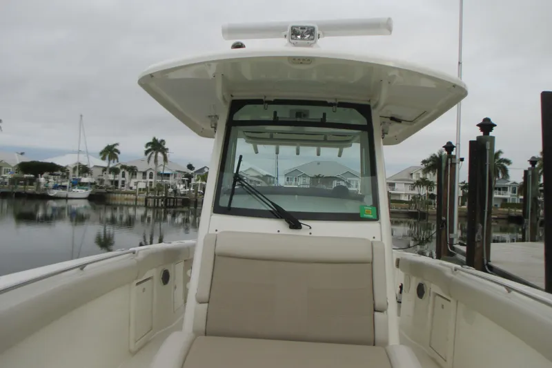 Slide: The Image of 2018 Boston Whaler 330 Outrage boat docked in a marina with palm trees. - 23