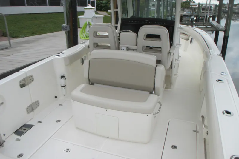 Slide: The Image of 2018 Boston Whaler 330 Outrage boat interior with seating and helm, docked by the water. - 3