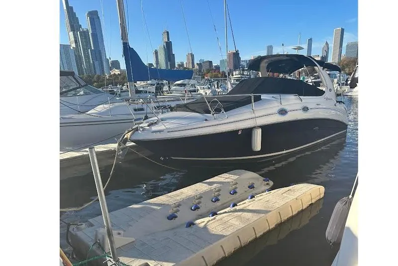 The Image of 2007 Sea Ray Sundancer 280 docked in a marina with city skyline backdrop. - 0
