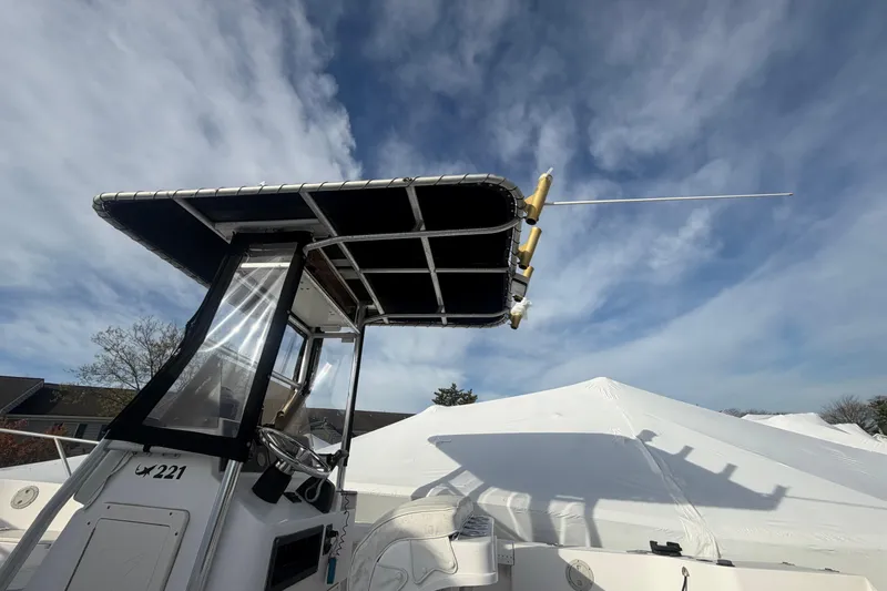 Slide: The Image of 1997 Mako 221 Center Console boat with T-top under a partly cloudy sky. - 11