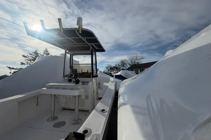 Slide: The Image of 1997 Mako 221 Center Console boat under a bright sky, partially covered. - 12