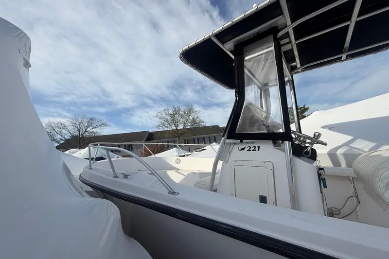 Slide: The Image of 1997 Mako 221 Center Console boat with protective cover, under a partly cloudy sky. - 13
