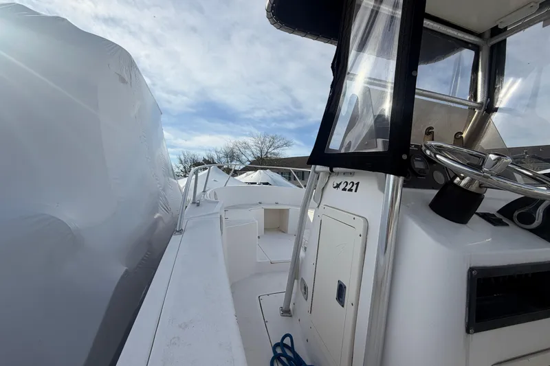 Slide: The Image of 1997 Mako 221 Center Console boat with steering wheel, under a cloudy sky. - 14