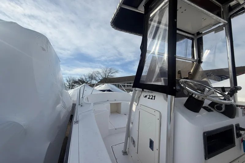 Slide: The Image of 1997 Mako 221 Center Console boat with steering wheel, under a clear blue sky. - 15