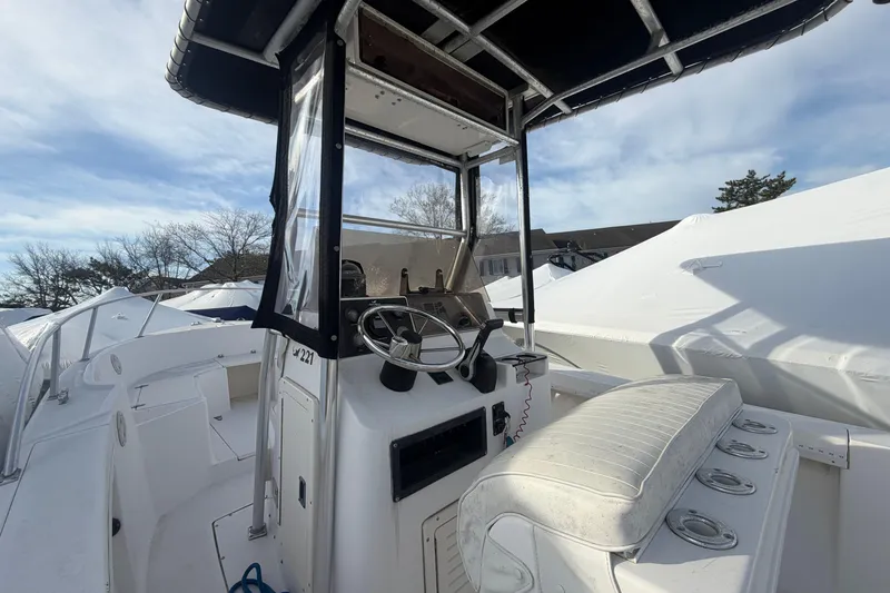 Slide: The Image of 1997 Mako 221 Center Console boat with steering wheel and seating, under clear sky. - 18