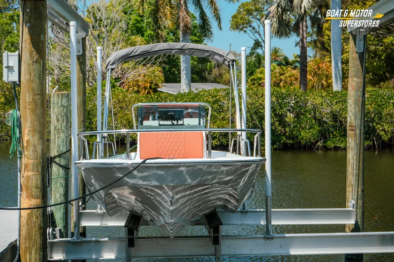 Slide: The Image of 1976 Boston Whaler 17 Montauk boat on lift, surrounded by lush greenery. - 14