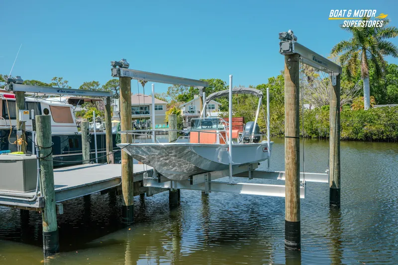 Slide: The Image of 1976 Boston Whaler 17 Montauk boat on lift at marina, sunny day, palm trees in background. - 15