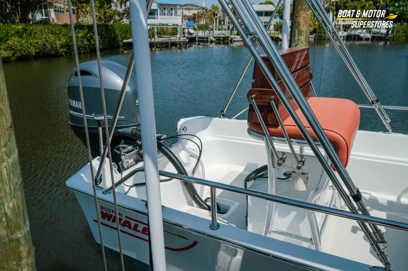 Slide: The Image of 1976 Boston Whaler 17 Montauk boat with Yamaha motor, docked in a serene marina. - 2