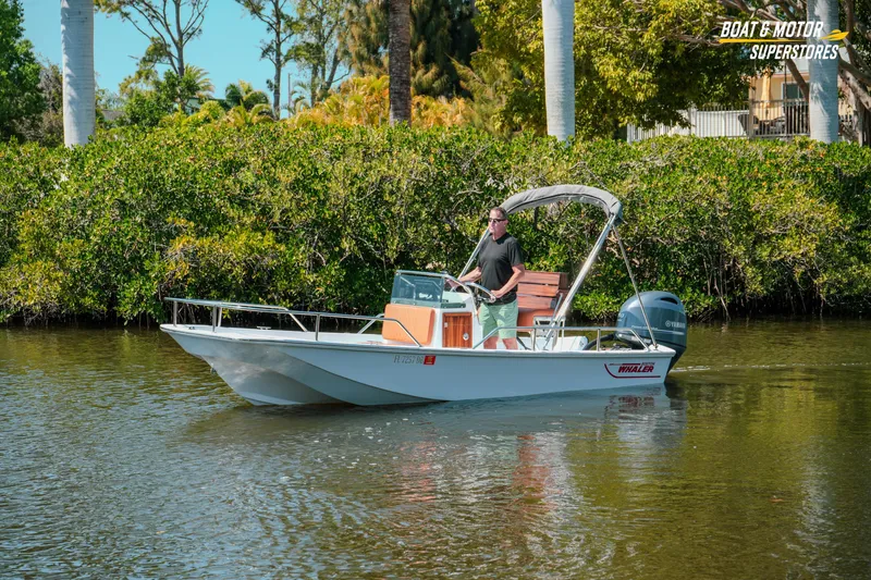 Slide: The Image of 1976 Boston Whaler 17 Montauk boat cruising on a calm river with lush greenery. - 33