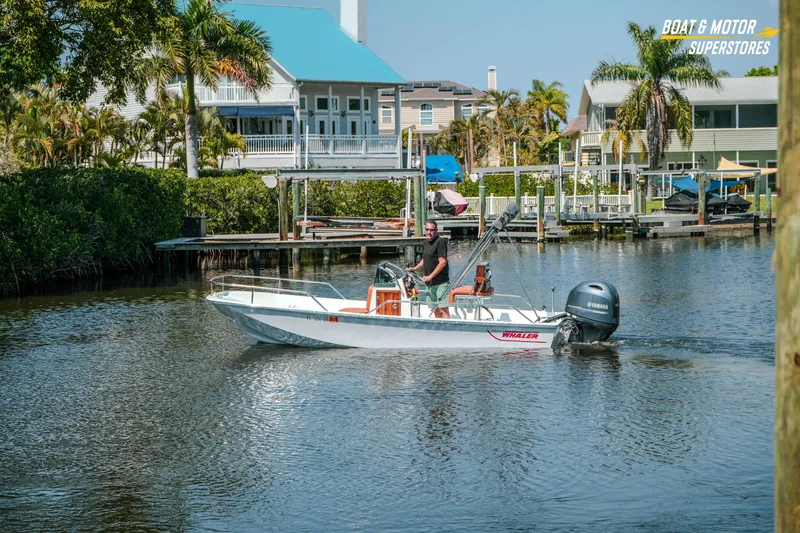 Slide: The Image of 1976 Boston Whaler 17 Montauk cruising on a scenic waterway near waterfront homes. - 37