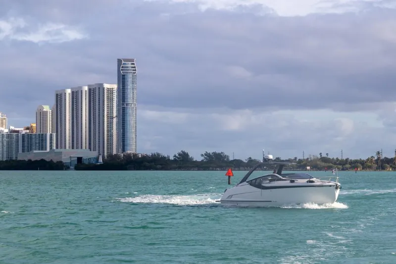 Slide: The Image of 2023 Fairline F//Line 33 Outboard cruising near city skyline on a cloudy day. - 4