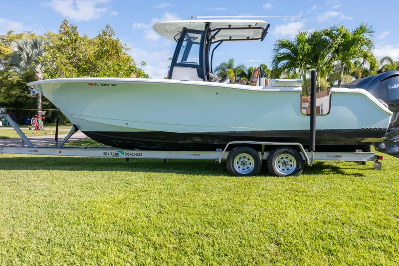 Slide: The Image of 2021 Sea Hunt Gamefish 27 boat on trailer, parked on grass with palm trees. - 10