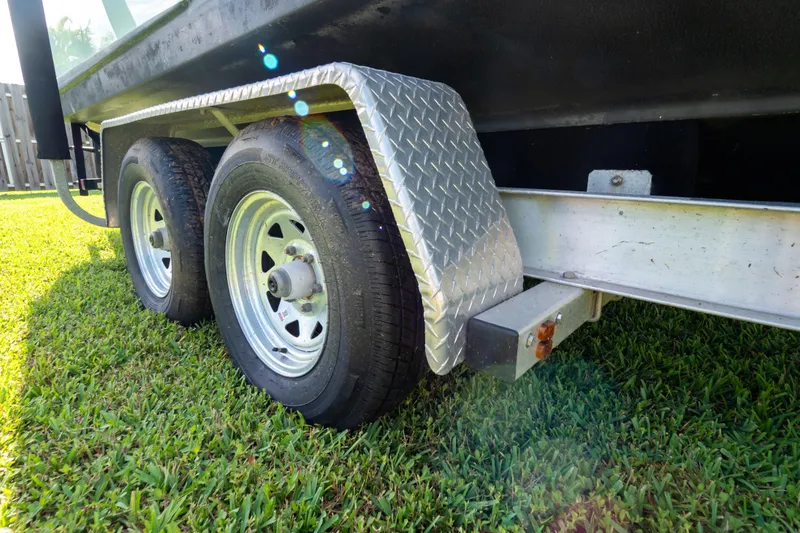 Slide: The Image of Trailer for 2021 Sea Hunt Gamefish 27 boat on grass, showcasing undercarriage and wheel. - 127