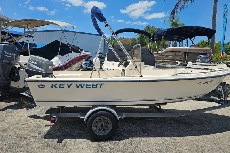 Slide: The Image of 2003 Key West 1720 Sportsman boat on trailer, surrounded by other boats, under a clear sky. - 3