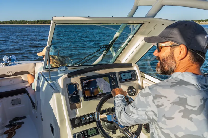 Slide: The Image of Man steering 2027 Sailfish 245 DC boat on open water, sunny day. - 3