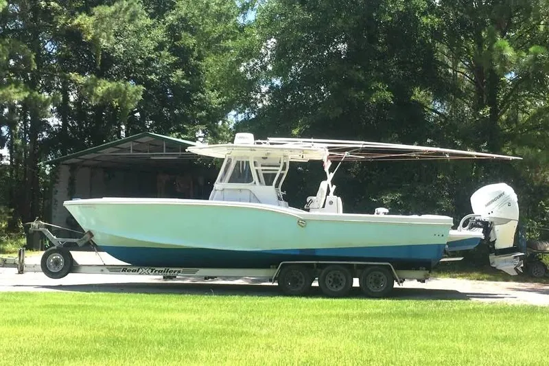The Image of Ocean Master 31 boat on trailer, 1999 model, parked outdoors with trees in background. - 0