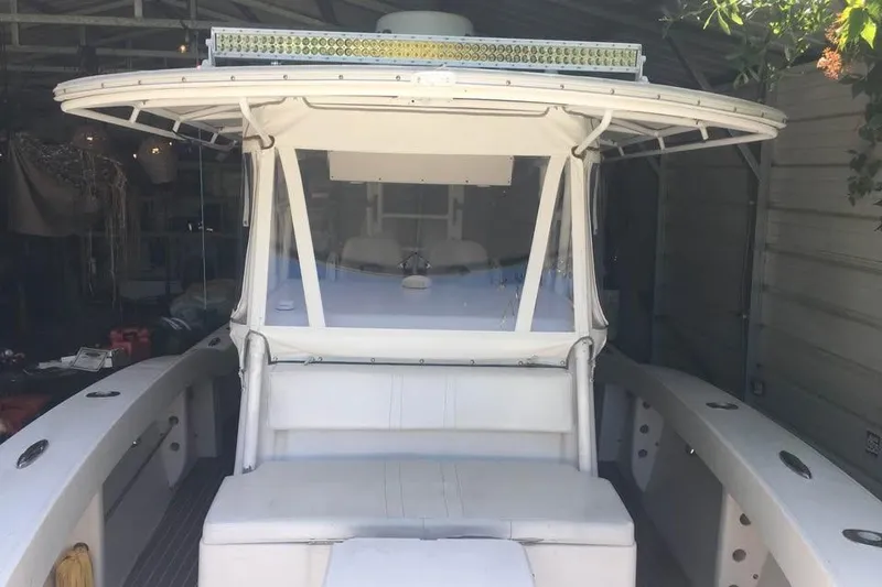Slide: The Image of 1999 Ocean Master 31 boat with white seating and canopy in a garage. - 10
