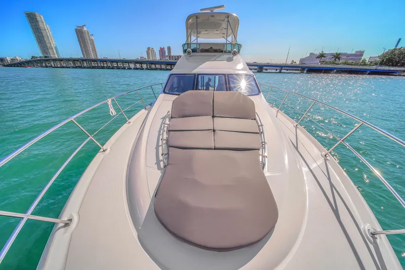 Slide: The Image of 2007 Sea Ray 52 Sedan Bridge yacht on turquoise water, city skyline in background. - 56