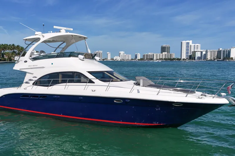 Slide: The Image of 2007 Sea Ray 52 Sedan Bridge yacht on turquoise water with city skyline backdrop. - 9