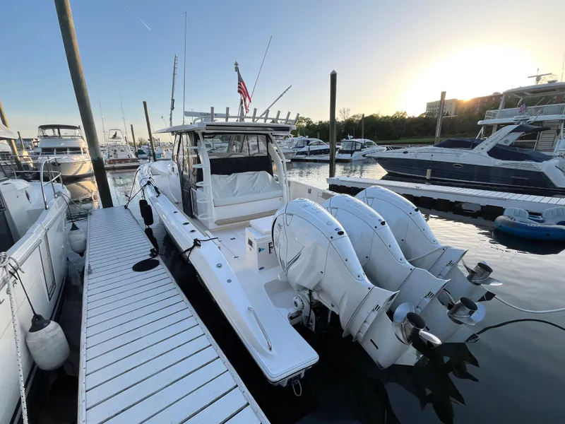 Slide: The Image of 2019 Pursuit S 408 Sport boat docked at marina with triple outboard engines. - 20