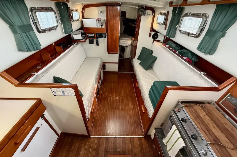 Slide: The Image of Interior of a 1975 Soverel 37 sailboat with wooden flooring and green curtains. - 11